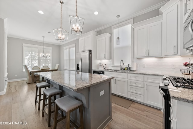 kitchen with white cabinetry, stainless steel appliances, hanging light fixtures, and a kitchen island