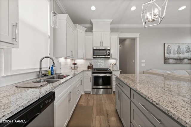 kitchen featuring white cabinetry, appliances with stainless steel finishes, light stone counters, and hanging light fixtures