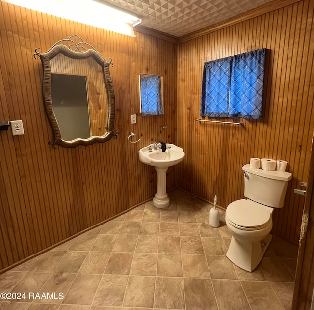 bathroom with tile patterned flooring, crown molding, toilet, and wooden walls