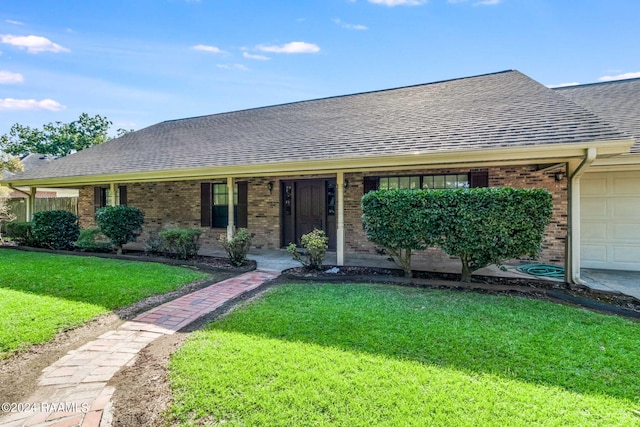 ranch-style house featuring a garage, a shingled roof, a front lawn, and brick siding