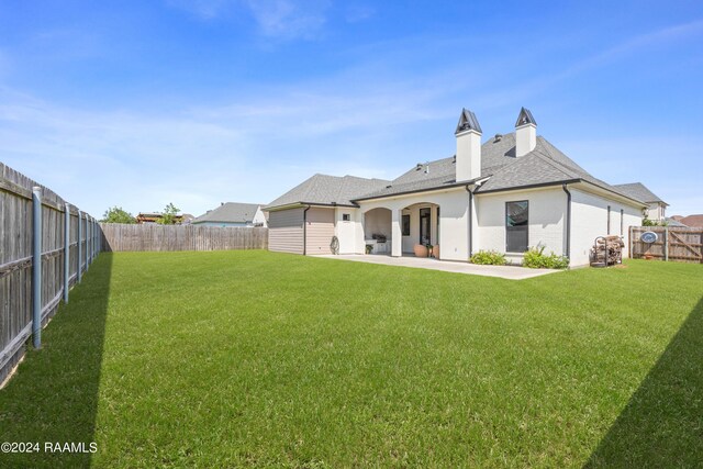 back of property with a patio area and a yard