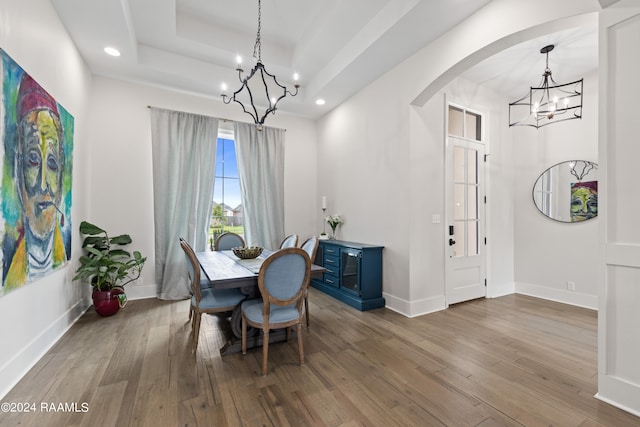 dining area featuring a notable chandelier, a tray ceiling, and hardwood / wood-style flooring