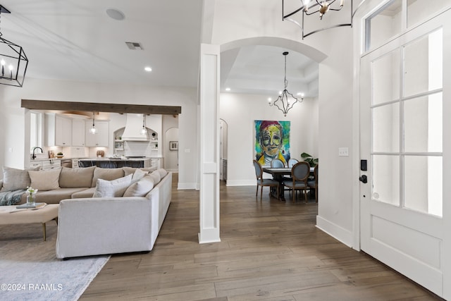 living room featuring an inviting chandelier, hardwood / wood-style flooring, a tray ceiling, and sink