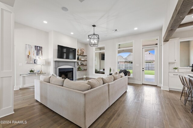 living room with a notable chandelier, beamed ceiling, and dark wood-type flooring