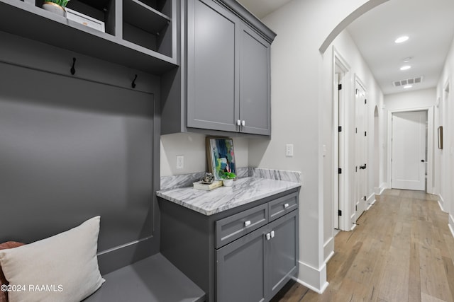 kitchen with light hardwood / wood-style flooring, gray cabinets, and light stone counters