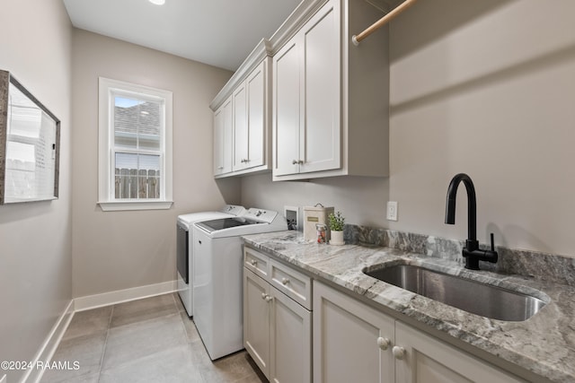 laundry area featuring washing machine and clothes dryer, cabinets, light tile patterned flooring, and sink