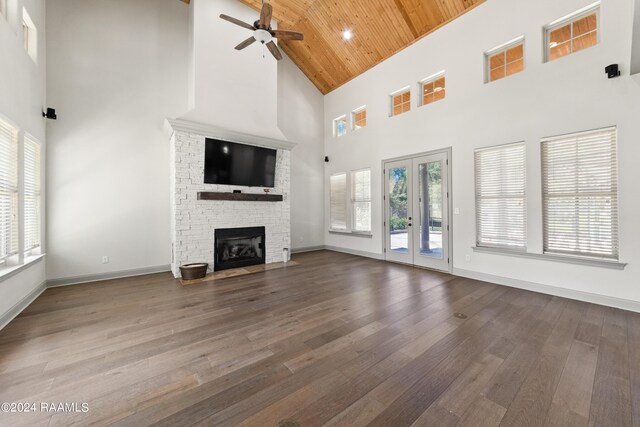 unfurnished living room featuring dark hardwood / wood-style flooring, wooden ceiling, a fireplace, high vaulted ceiling, and ceiling fan