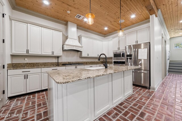 kitchen featuring white cabinets, decorative light fixtures, appliances with stainless steel finishes, sink, and premium range hood