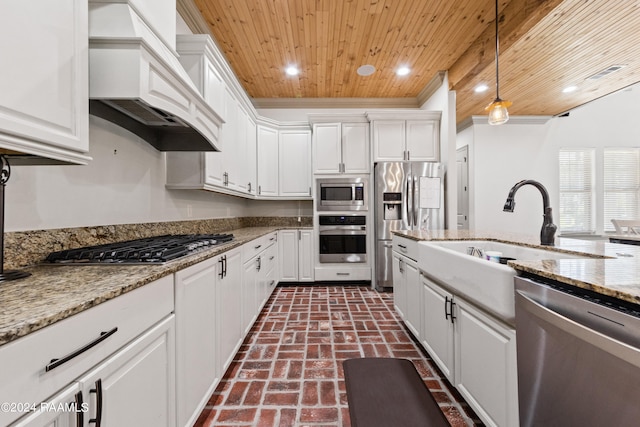 kitchen featuring appliances with stainless steel finishes, white cabinetry, custom range hood, and hanging light fixtures