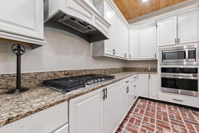 kitchen featuring stone countertops, stainless steel appliances, custom exhaust hood, and white cabinets