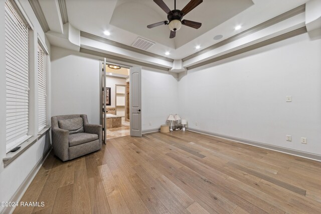 unfurnished room with light wood-type flooring, a tray ceiling, crown molding, and ceiling fan