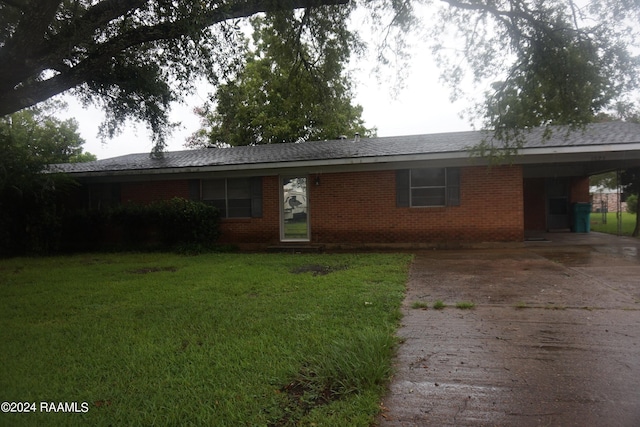 view of front of property featuring brick siding, driveway, a front yard, and a carport