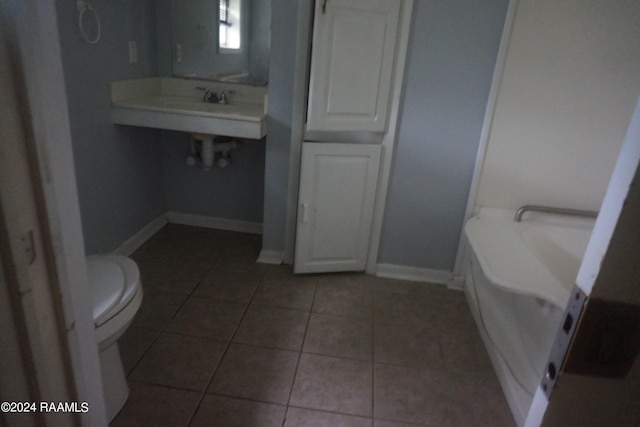 full bathroom featuring tile patterned floors, baseboards, toilet, and a tub