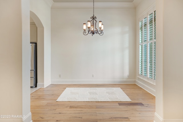 unfurnished room featuring crown molding, an inviting chandelier, and light wood-type flooring