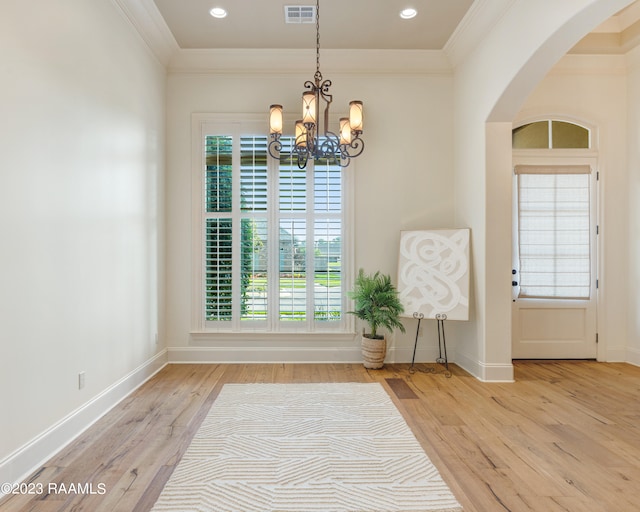 interior space featuring light hardwood / wood-style floors, crown molding, and an inviting chandelier