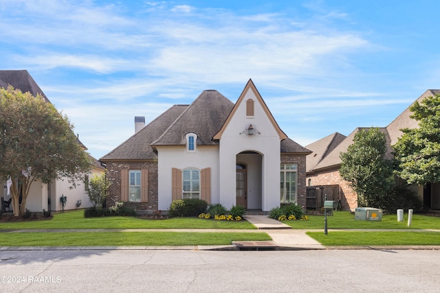 french provincial home with a front yard