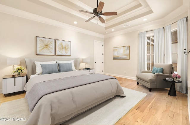 bedroom with ceiling fan, a raised ceiling, and light hardwood / wood-style flooring