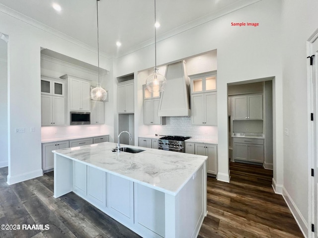 kitchen featuring stainless steel appliances, a kitchen island with sink, sink, and custom range hood