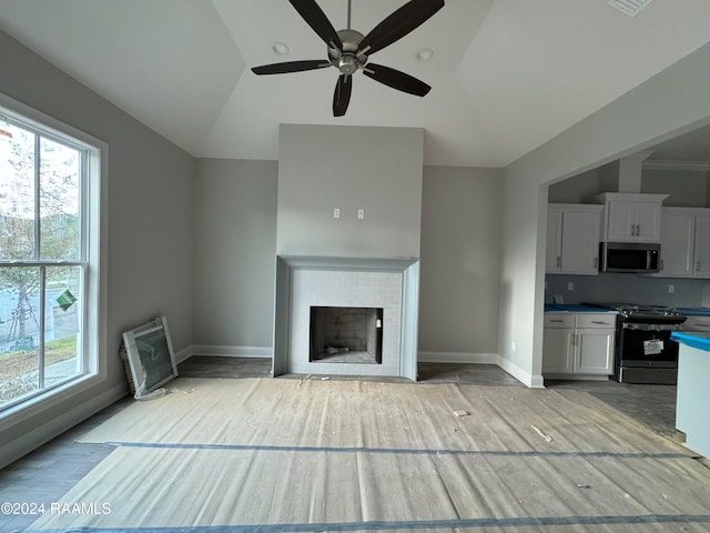 unfurnished living room featuring plenty of natural light, ceiling fan, and lofted ceiling