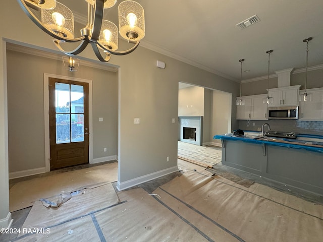 kitchen with tasteful backsplash, ornamental molding, decorative light fixtures, a notable chandelier, and white cabinetry