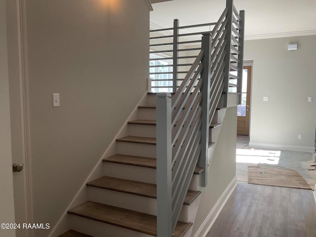 staircase with hardwood / wood-style flooring, a wealth of natural light, and crown molding