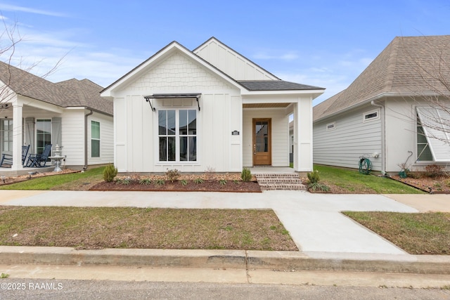 view of front of home featuring a front lawn, a porch, board and batten siding, and roof with shingles