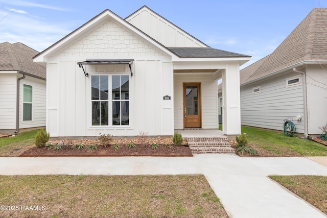 modern farmhouse with board and batten siding, a front yard, and roof with shingles