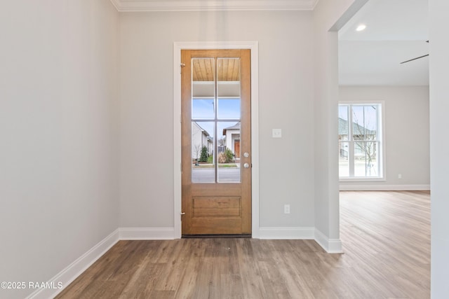 entryway featuring light wood-style floors, ornamental molding, and baseboards