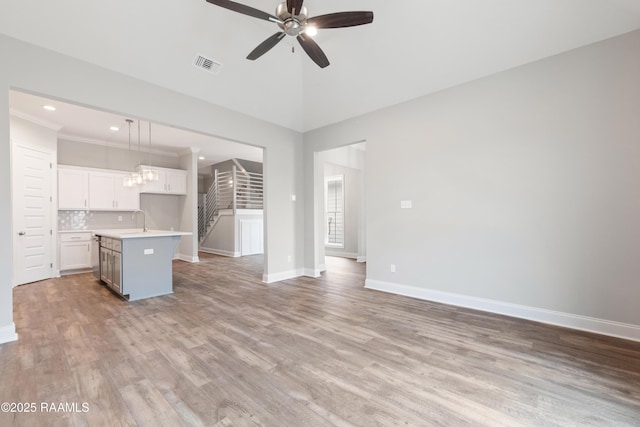 unfurnished living room with visible vents, stairway, a ceiling fan, light wood-type flooring, and baseboards