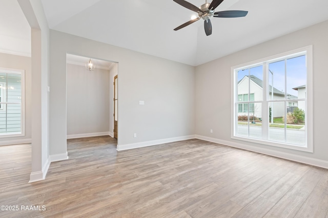 empty room featuring light wood-style flooring, baseboards, vaulted ceiling, and ceiling fan with notable chandelier