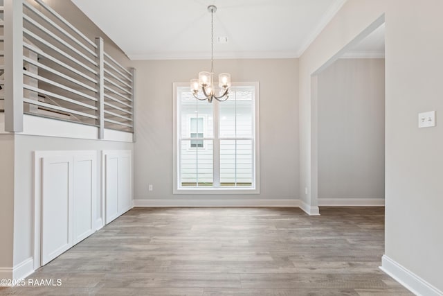 unfurnished dining area featuring ornamental molding, a chandelier, baseboards, and light wood finished floors