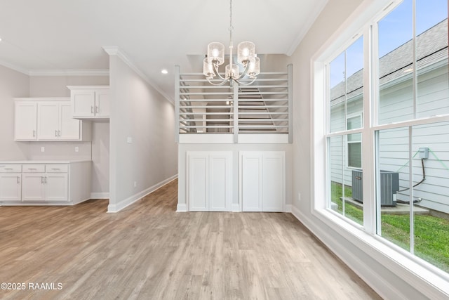 unfurnished dining area with ornamental molding, light wood-style flooring, and baseboards