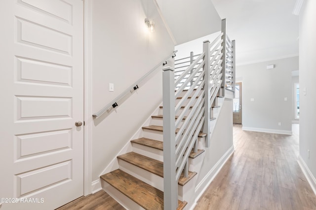 stairway with ornamental molding, baseboards, and wood finished floors