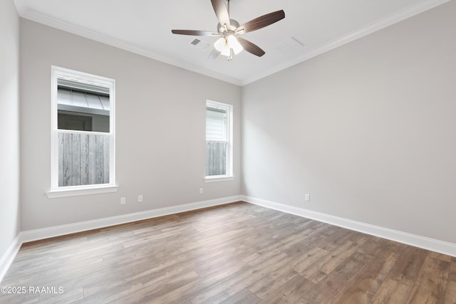 unfurnished room with visible vents, crown molding, baseboards, and wood finished floors