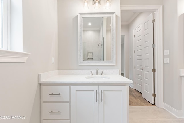 bathroom with baseboards, a tile shower, vanity, and crown molding