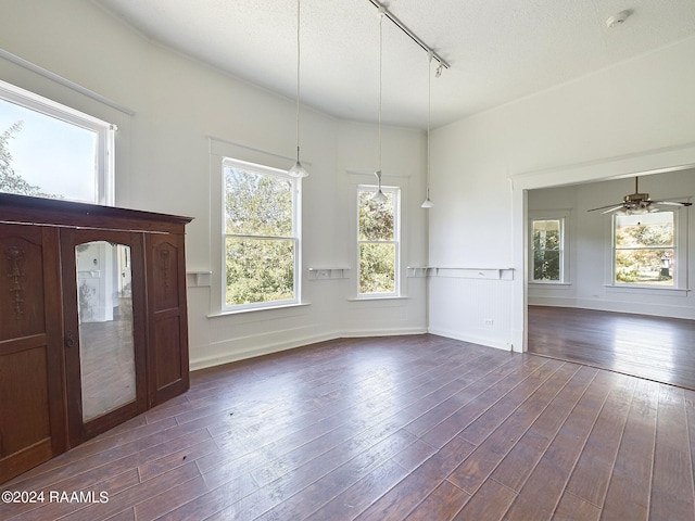 interior space with ceiling fan, a textured ceiling, dark hardwood / wood-style floors, and rail lighting