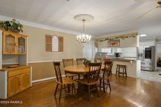 dining area with crown molding, dark wood-type flooring, and an inviting chandelier