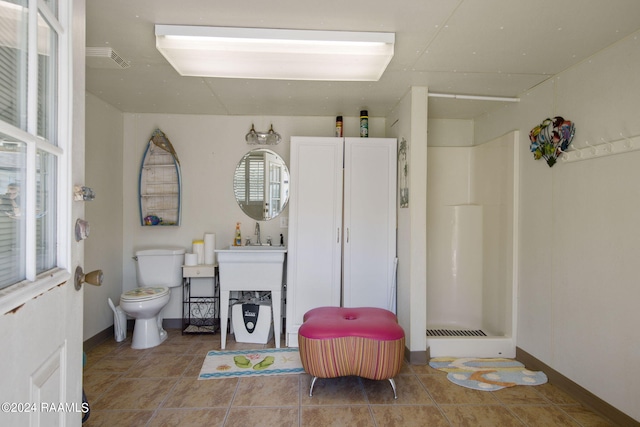 bathroom with toilet, walk in shower, and tile patterned floors