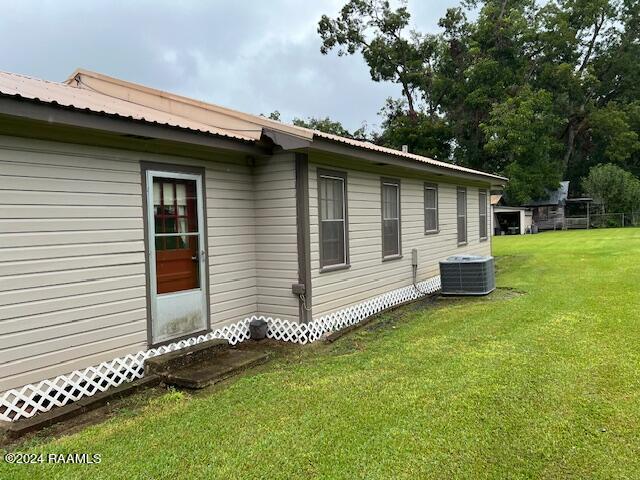 view of side of property with a lawn and central AC