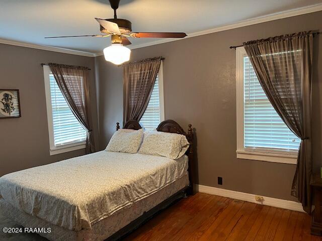 bedroom featuring dark wood-type flooring, ceiling fan, and crown molding