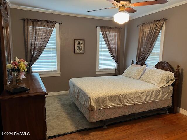 bedroom featuring multiple windows, hardwood / wood-style flooring, and ornamental molding