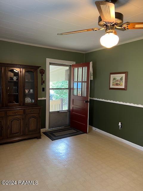 doorway featuring ceiling fan and ornamental molding