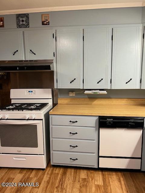 kitchen featuring white cabinets, light wood-type flooring, ornamental molding, and white appliances