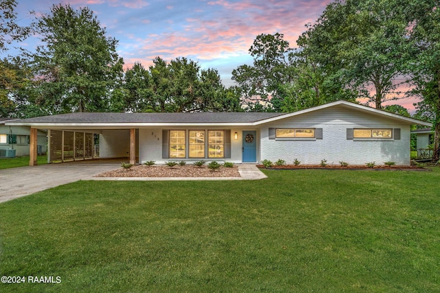 single story home with central air condition unit, a yard, and a carport