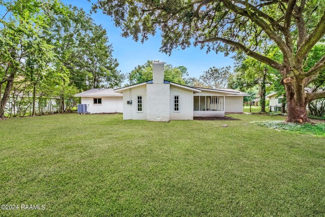 back of property featuring a lawn and central AC