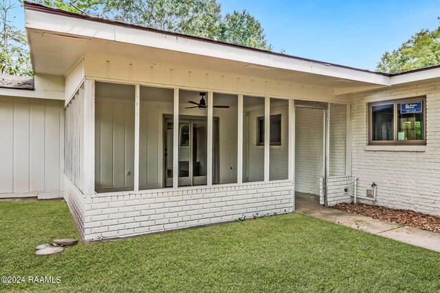 rear view of house with ceiling fan and a lawn