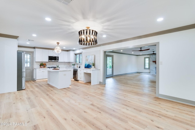 kitchen featuring light wood-type flooring, white cabinets, stainless steel appliances, decorative light fixtures, and ornamental molding