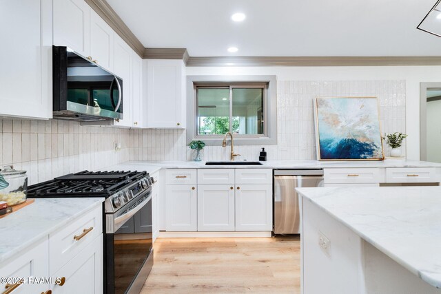 kitchen featuring sink, light hardwood / wood-style flooring, white cabinetry, stainless steel appliances, and light stone countertops