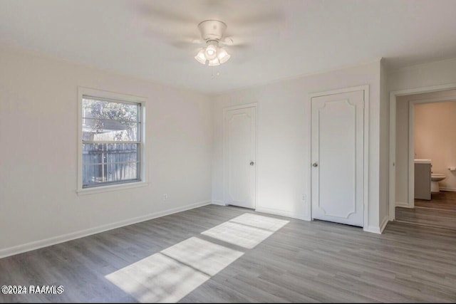 unfurnished bedroom featuring connected bathroom, light wood-type flooring, and ceiling fan