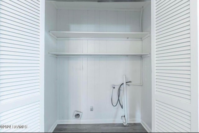 laundry room with electric dryer hookup, washer hookup, hardwood / wood-style flooring, and wooden walls